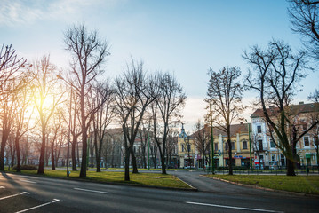 Arad, Romania - January 01, 2013: Park in the city of Arad, Romania, with buildings in the background and a strong sun which sets