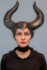 Naklejka premium Maleficent - beautiful woman from a fairytale with hair horns and creative make-up for the Halloween party