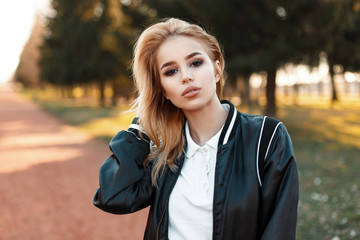 Portrait of a beautiful blond woman in a bomber jacket in white polo on a sunny day