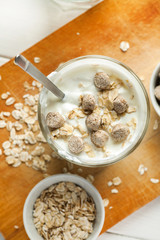 Yogurt in glass with oat flakes and wheat bran in it, vertical