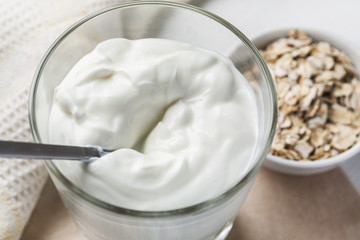 Full glass of yogurt with metal spoon in it, closeup shot