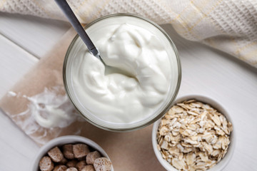 Yogurt with wheat bran and oat flakes on a wooden table, top view