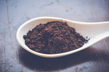 coffee powder on white spoon on wooden table