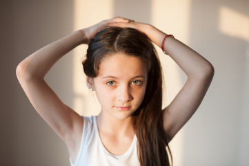 adorable young girl doing her hair with both hands