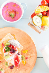 Toast and fruit total milk yogurt with fried egg in a frying pan on wood Top view.