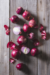 Red onion bulbs lying on an old wooden table.