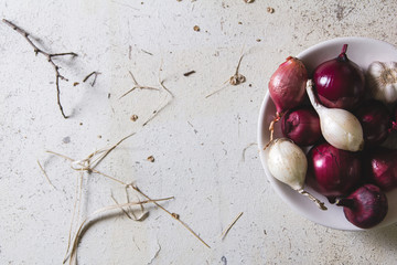 Red and white onion bulbs in the plate on old wooden painted table