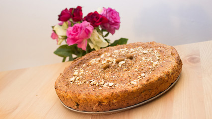 Selbstgebackenes Brot mit Nüssen, Mandeln, Amaranth, Leinsamen bestreut mit Rosen im Hintergrund