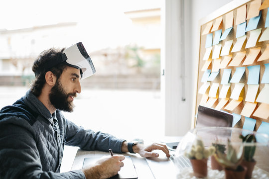 Man with Virtual Reality Glasses working  with graphics tablet and laptop at his office