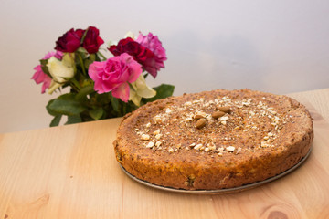 Selbstgebackenes Brot mit Nüssen, Mandeln, Amaranth, Leinsamen bestreut mit Rosen im Hintergrund