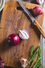 Red onion bulb on brown cutting board.