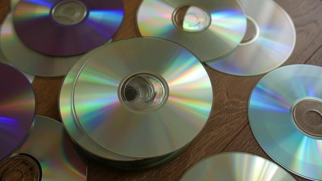 Optical Discs falling onto big pile of DVDs or CDs. Slow motion.