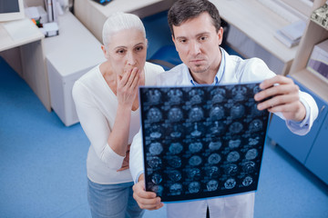 Serious shocked woman looking at her brain X ray images