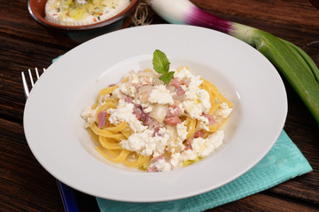 Dish of pasta noodles with cottage cheese bacon and onion shallot
