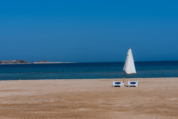 Idyllic tropical beach with golden sand, sun beds and umbrella