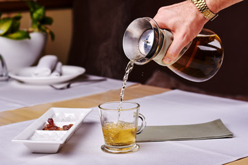 Waiter pouring tea into a white cup in cafe