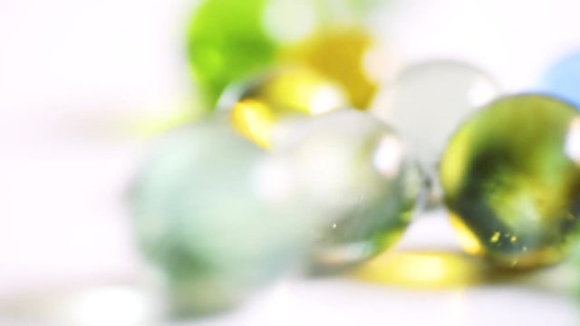 Colorful rolling glass marbles on white background.