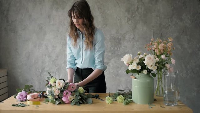 Female florist making beautiful bouquet at flower shop, peone and roses