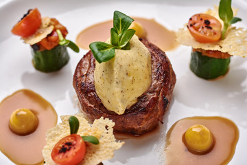 Beef filet dinner entree with garnish and brown sauce displayed on a white dinner plate. Horizontal shot.