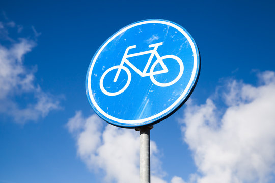 Bicycle lane, round blue road sign over cloudy sky