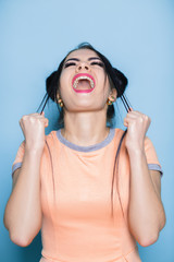 Naklejka premium Furious and frustrated woman screaming on blue background. girl cries out in despair