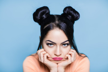 portrait of sad and upset brunette woman with hair of mouse on blue background