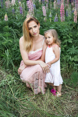 Mom and daughter in a blooming garden at summer