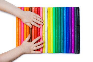 Child hands playing with colorful plasticine. Set of plasticine palettes on white background, rainbow colors