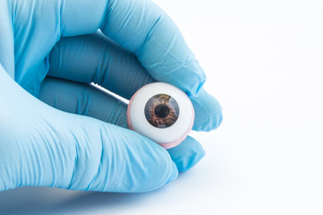 Ophthalmologist or surgeon holds in hand dressed in a blue glove eye (eyeball). Concept photo for...