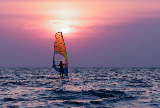 Man playing windsurfing at sunset.