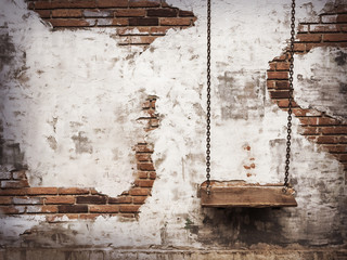 Empty chain swing against old brick wall background