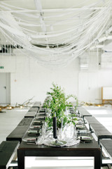 Stylish meals and a table, loft. Design room in the loft style. Black table, chairs, dishes, candles. Jars with greens.