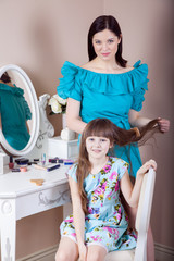 Mother hairdressing her preteen beautiful daughter at home.