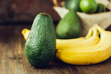 Avocado and banana over brown wooden background.