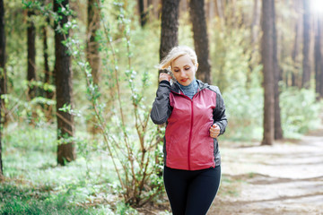 A woman runs in the woods. Blonde girl is engaged in sports Jogging