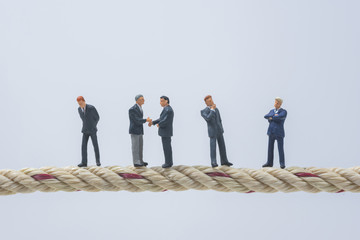 business miniature people standing on a rope