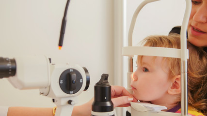 Child's optometry - little girl hecks eyesight in eye ophthalmological clinic
