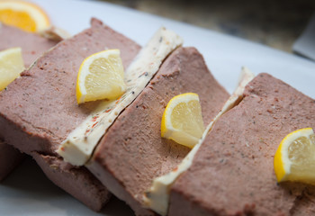 Starter plate of liver pate or pate de campagne, a country style meat mixed loaf cut in slices and garnished with lemon, appetizers, hors d'oeuvre or tapas selection ready at a self service buffet