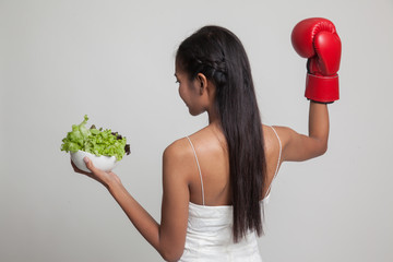 Young Asian woman with boxing glove and salad.