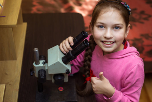 A little girl at home conducting research with a microscope
