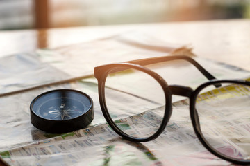 Compass and eye glasses on map, travel concept