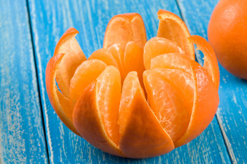 one peeled tangerine on a blue wooden background