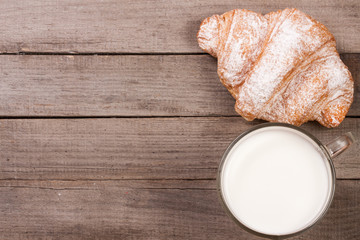 glass of milk with croissants on old wooden background with copy space for your text. Top view