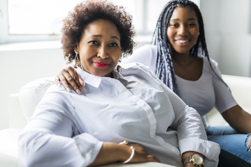 affectionate mother and daughter sitting on sofa