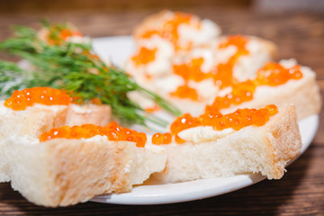 Red caviar. Caviar on a piece of bread and butter. A delicacy caviar with oil on a table.