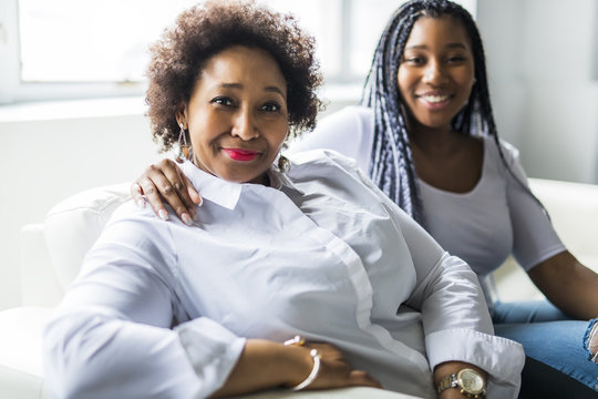 Affectionate Mother And Daughter Sitting On Sofa