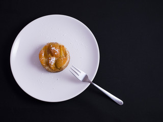 Small french apricot tart on white plate isolated on black background