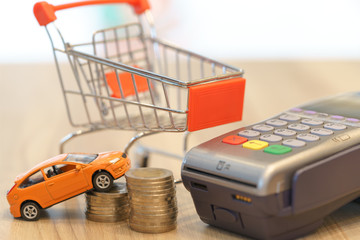 Concept of buying new car by money with red shopping cart and magnetic card.