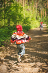 Group of little kids running in the forest. Middle spring green pine forest hike in Waldorf...