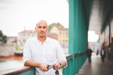 Young man caucasian outdoor in the city looking camera, smiling - customer, city living, positive feelings concept